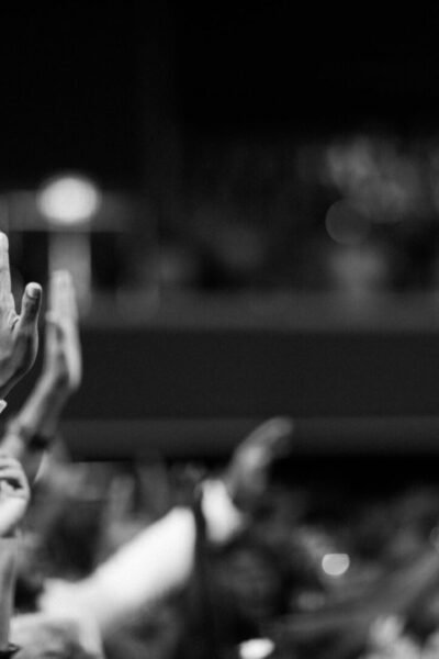pexels-photo-2014773-2014773 Black and white image of audience with hands raised, capturing concert energy.