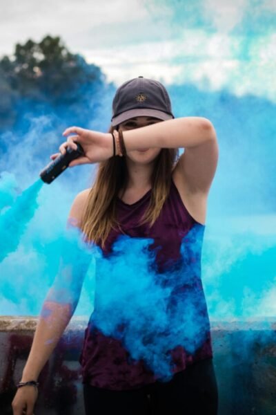pexels-photo-445109-445109 A stylish woman surrounded by bright blue smoke outdoors, creating a dynamic fashion statement.